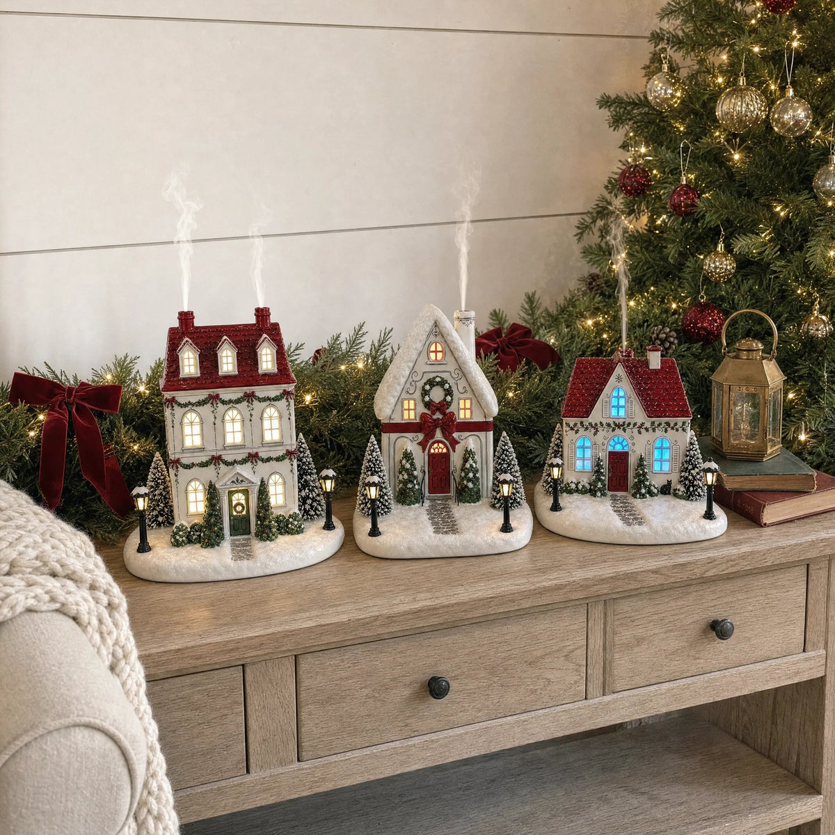 Three Mistletoe Lane Christmas diffusers glowing beside a Christmas tree